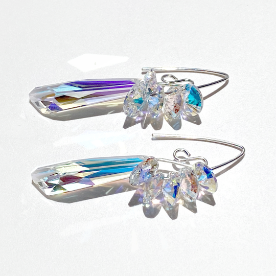 A pair of silver crystal earrings with iridescent stones, handcrafted with a gold trim jewelry box.
